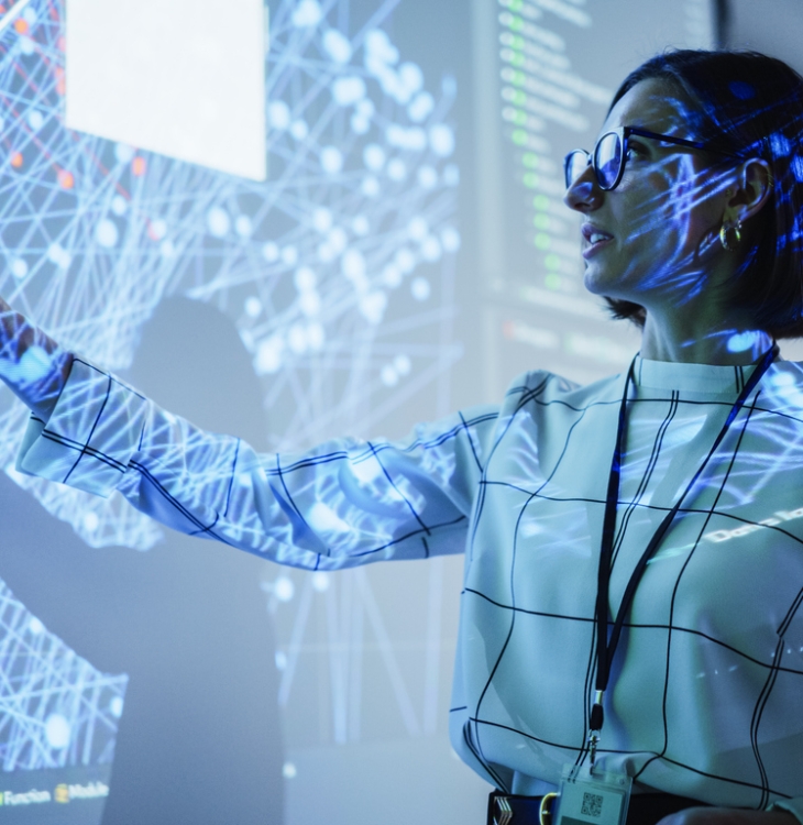 Young Female Teacher Giving a Data Science Presentation in a Dark Auditorium with Projecting Slideshow with Artificial Intelligence Neural Network Architecture. Business Startup and Education Concept